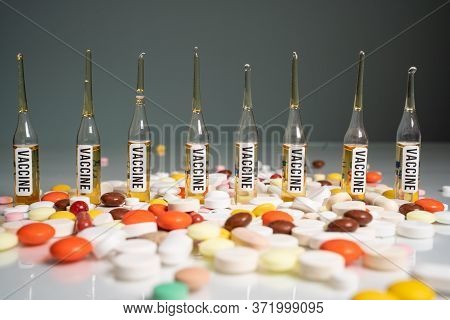 Many Tablets And Pills In Front Of Glass Vaccine Bottles. Mandatory Vaccinations, Vaccine Of Coronav