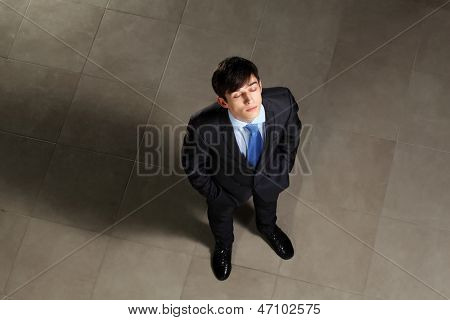 Image of young businessman with his eyes closed looking above. Top view