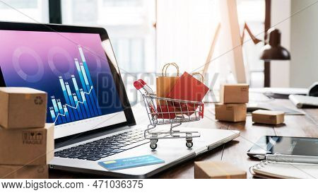 Shopping Bags In Shopping Cart And Credit Card On Laptop With Paper Boxes On Table And Sales Data Ec