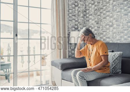 Sad Depressed Middle Aged Mature Woman Sitting Alone At Home Touching Head Feeling Headache Migraine