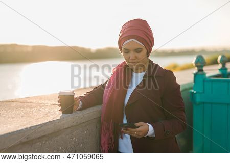 Modern Arab Girl In Hijab Walking By Street And Drinking Coffee Take Away In Spring Time Morning