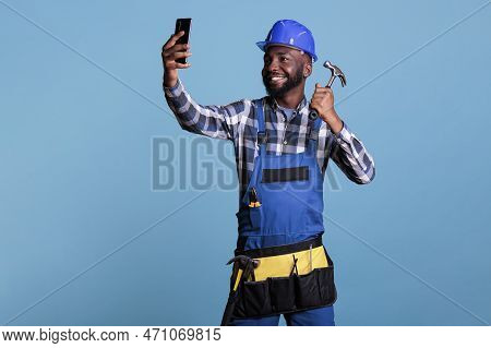 African American Contractor Taking Selfie With Mobile Phone Holding Hammer Against Blue Background I