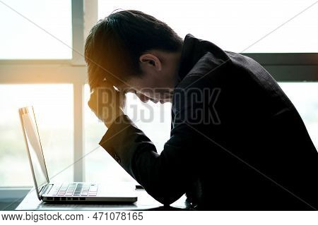 A Man Sitting Down, His Face Unsettled. At The Computer Desk He Has Headaches And Stress. Cause Of H