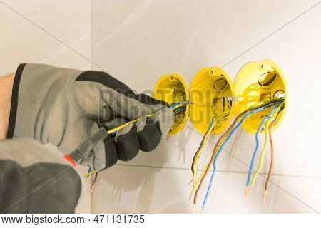 Electrician Hands Mounting Electric Wall Receptacle Fitting Into Place