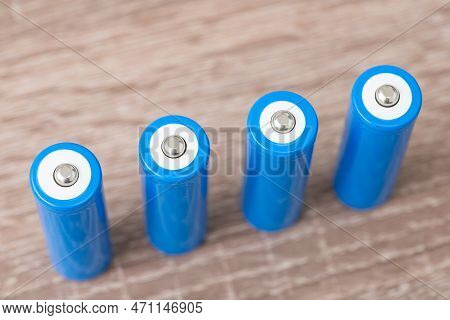 Four Blue Generic Batteries On Wooden Table. New Li-ion Batteries Concept, Using Accumulators