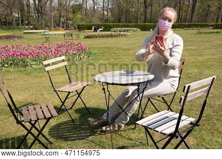 Young Woman In A Protective Mask Takes A Selfie With Blooming Sprimg Tulips