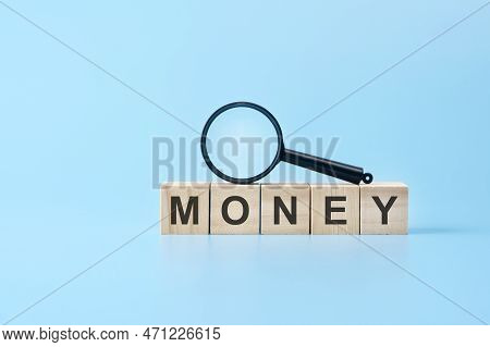 Wooden Blocks With The Text: Money With Magnifying Glass. Business Concept