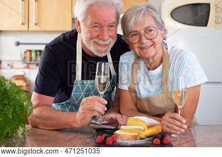 Beautiful Senior Couple In The Home Kitchen Holding A Glass Of Wine Ready To Eat Their Homemade Plum