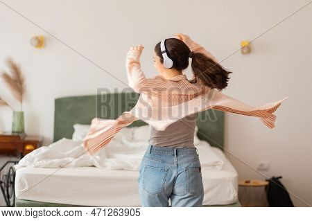 Happy Young Caucasian Woman Wearing Headphones Spinning Dance And Enjoy Life. Back View. Leisure In 