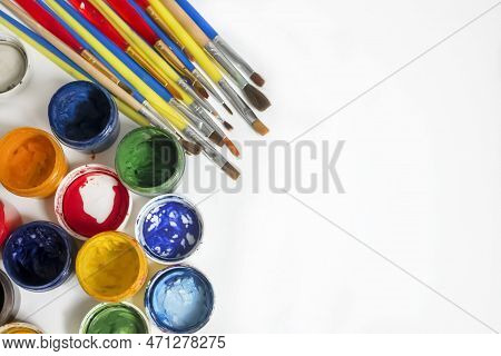 Jars Of Colored Paint Stand Next To The Brushes. For Artists, There Are A Lot Of Paints And Brushes.