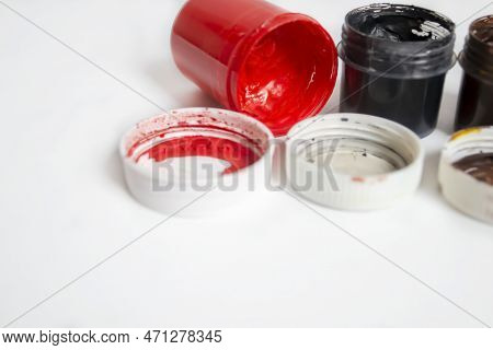 Red Watercolor Next To Black. Colored Paints On The Table. Jars With Red And Black Watercolors On A