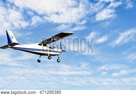 Single engine ultralight plane flying in the blue sky with white clouds