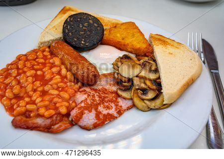 White Board With Full English Breakfast With Bacon, Fried Egg, Beans, Tomato, Roasted Sausage, Black