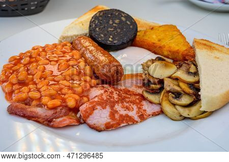 White Board With Full English Breakfast With Bacon, Fried Egg, Beans, Tomato, Roasted Sausage, Black