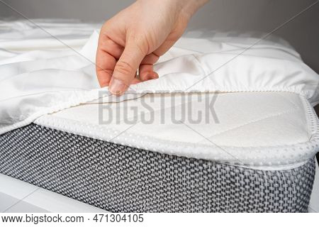 A White Satin Sheet With An Elastic Band Is Put On The Mattress Of The Bed, A Close-up Of The Hands.