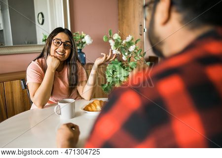 Young Diverse Loving Couple Eating Croissant And Talks Together At Home In Breakfast Time. Communica