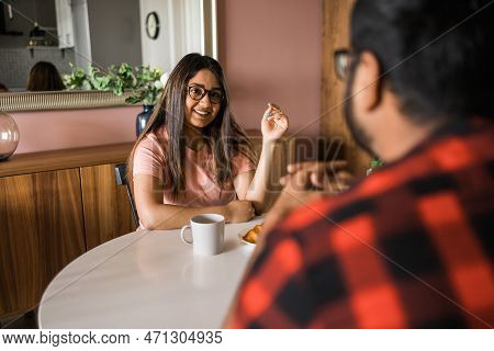 Young Diverse Loving Couple Eating Croissant And Talks Together At Home In Breakfast Time. Communica