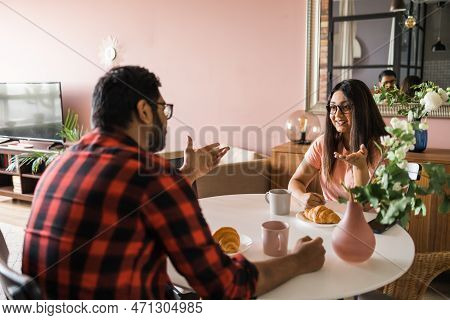 Young Diverse Loving Couple Eating Croissant And Talks Together At Home In Breakfast Time. Communica