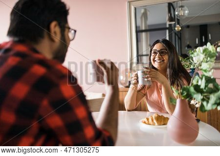 Young Diverse Loving Couple Eating Croissant And Talks Together At Home In Breakfast Time. Communica