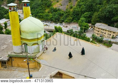 Masuleh, Iran - May 2022: Woman In Traditional Clothing Walk By Mosque In Masouleh Mountains Village