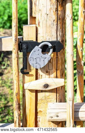 New Metal Padlock On A Bright Yellow Wooden Fence In The Village