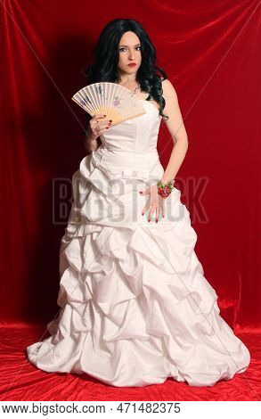 Woman Wearing Satin Corset Style Ball Gown Wedding Dress On Red Velvet Background