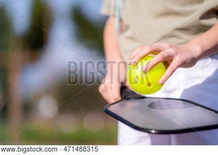 Pickleball Paddle And Yellow Ball Close Up In Children Hands, Leisure Outdoor Sport Activity.