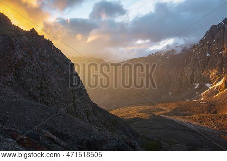 Scenic Alpine Landscape With Mountain Wall In Low Clouds In Golden Sunrise Colors. Colorful View To 