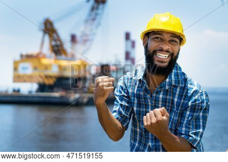 Motivated African American Offshore Worker With Digger And Plattform And Ship At Blue Ocean