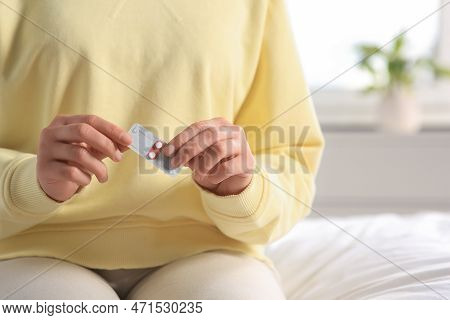 Woman Holding Blister Of Emergency Contraception Pills In Bedroom, Closeup