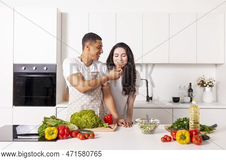 Multiracial Couple In Kitchen Preparing Salad Together, American Guy And European Girl Preparing Veg