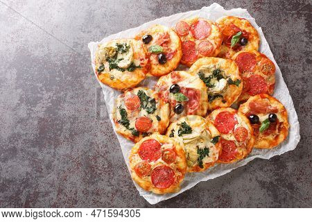 Hot Assorted Mini Pizza Or Pizzette With Various Toppings Close-up On Parchment On The Table. Horizo