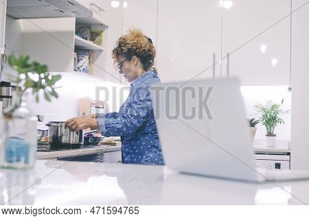 One Woman Cooking Alone At Home Using Pots And Laptop Computer To Watch Online New Recipe. Food Prep