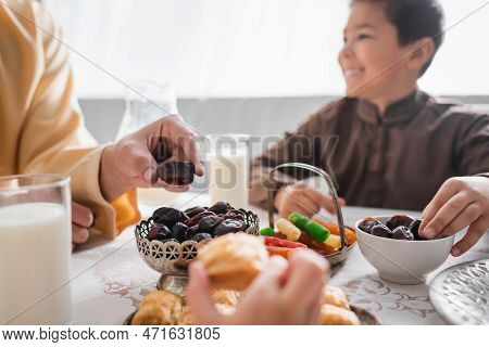 Muslim Man Taking Date Fruit Near Kids During Suhur Breakfast At Home.