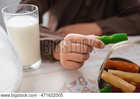 Cropped View Of Muslim Boy Holding Cevizli Sucuk Near Glass Of Milk During Suhur Breakfast.