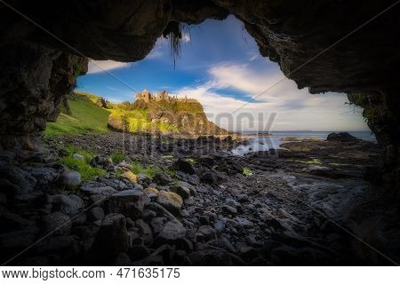 Dunluce Castle Seen From A Small Cave On A Shoreline, Nested On The Edge Of Cliff, Part Of Wild Atla