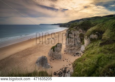 People Walking On White Rocks Beach With Limestone Rock Formations At Sunset, Causeway Coast, Wild A