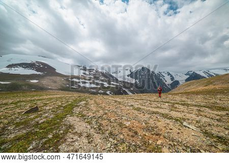 One Man Walks With View To High Snowy Mountain Range With Sharp Tops And Glaciers Under Gray Cloudy 