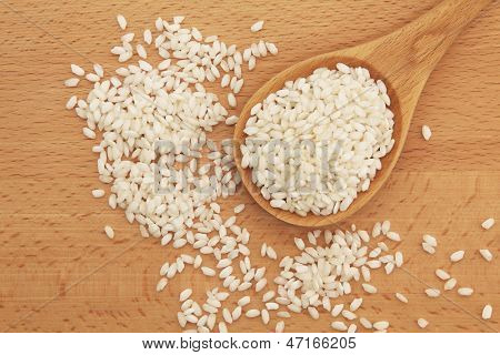 Risotto arborio hvide ris i en bøg træ ske over træplade.
