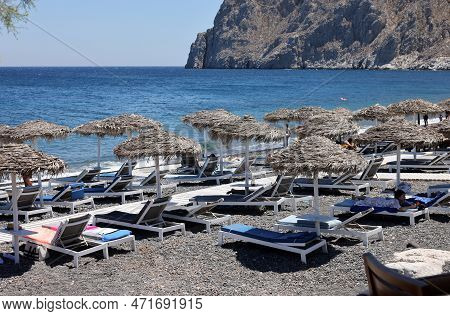 Kamari, Santorini, Greece - June 30, 2021: Sun Loungers On The Black Volcanic Beach Of Kamari In San