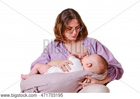 Woman Mother Breastfeeds An Infant Baby Sitting On A Home Sofa, Isolated On A White Background. Mom 
