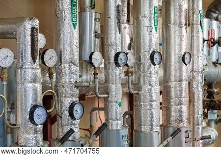 Plumbing Pipes In The Basement With Pressure Gauges On Them. Russian Inscriptions On Pipes