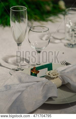 White Napkin On A Plate And A Sign On The Wedding Table. Empty Glasses