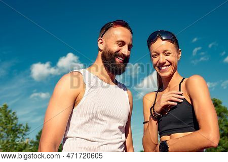Althetes Man And Woman 25-35 Years Old, Posing For The Camera, Smiling, Running Against The Backdrop