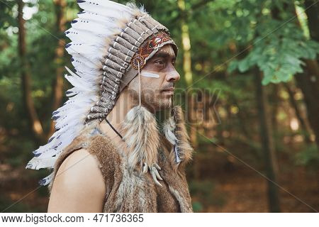 A Man In Traditional Native American Clothing In The Evening Forest