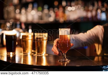 Bartender Hands A Glass Of Tulip Frothy Draft Beer To Bar Counter