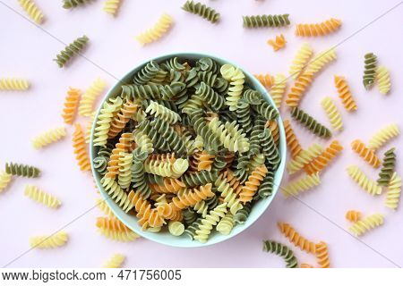 Organic Fusilli Tricolore Spilling On Pink Background