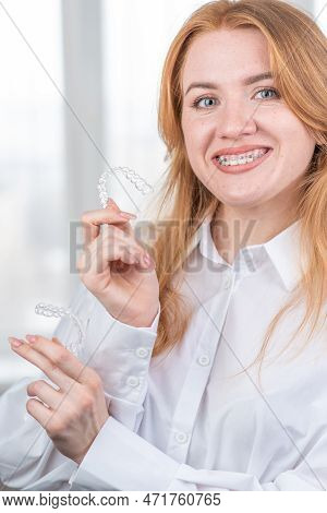 Dental Care.smiling Girl With Braces On Her Teeth Holds Aligners In Her Hands And Shows The Differen
