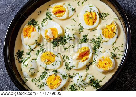 Close-up Of Senfeier,  Hard Boiled Eggs In Rich Creamy Mustard Sauce In Black Bowl On Concrete Table