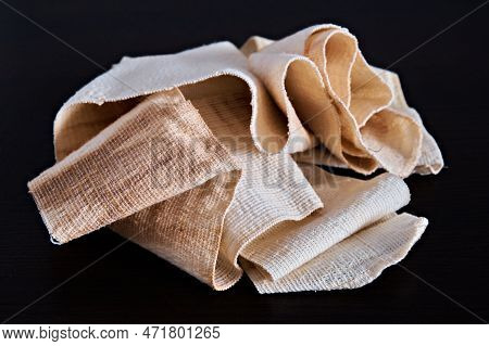 Dirty, Used Medical Elastic Bandage, On A Dark Background. Concept Of Medicine. Close-up